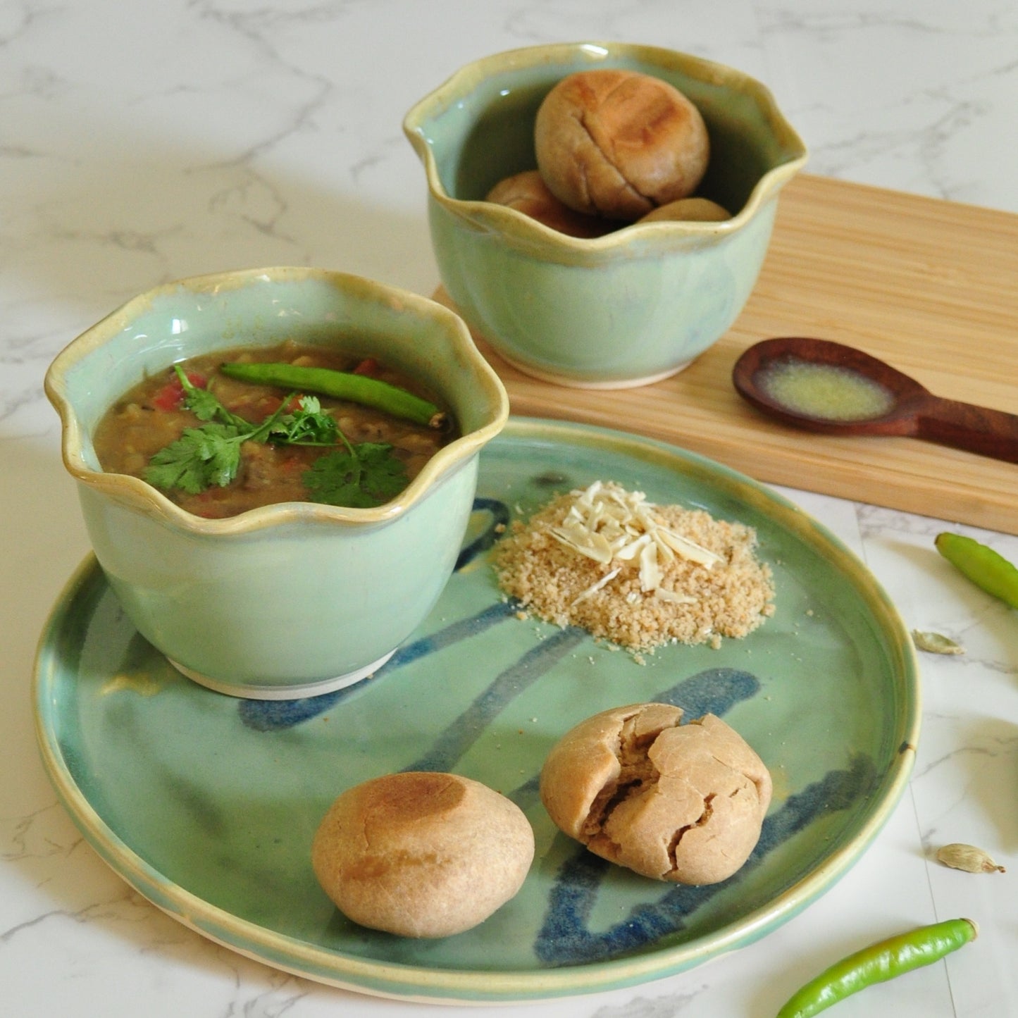 Dal baati churma served in circular plate with splashes, wavy rim bowl from Magic Mint green collection.