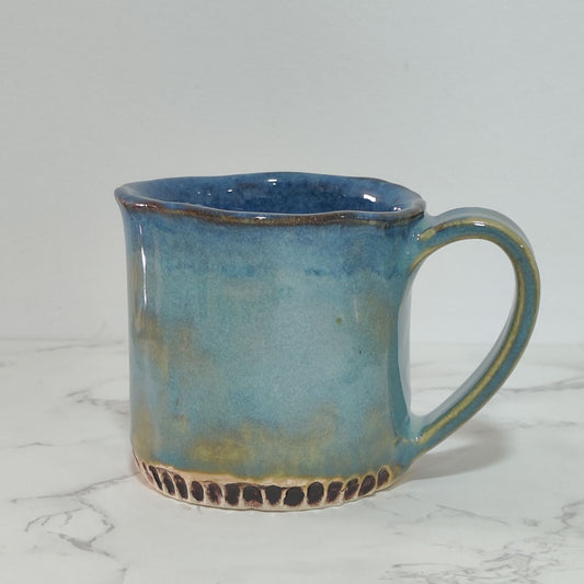 Mug glazed in shades of blue color, made using slab technique of pottery hand-building.