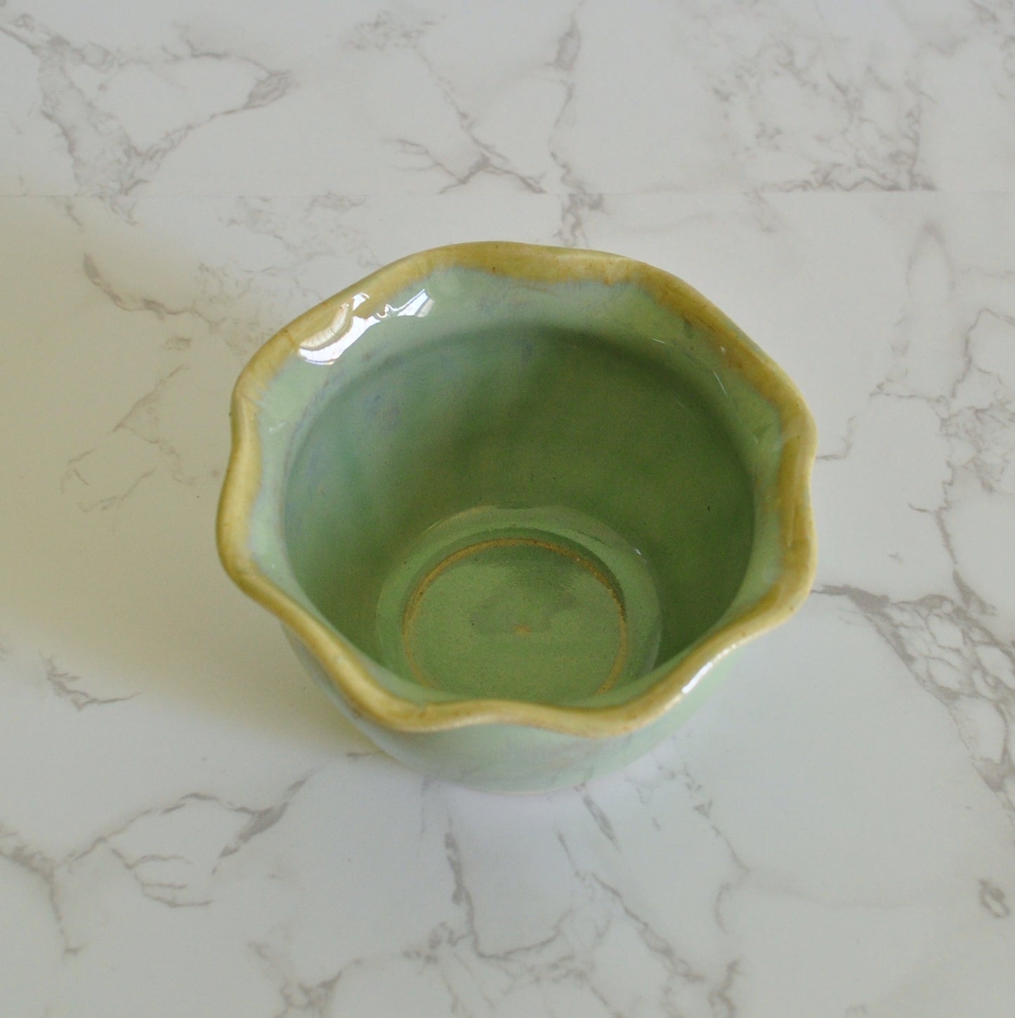 Top view of handmade ceramic bowl with wavy rim, made in stoneware clay and glazed in Magic Mint green glaze.
