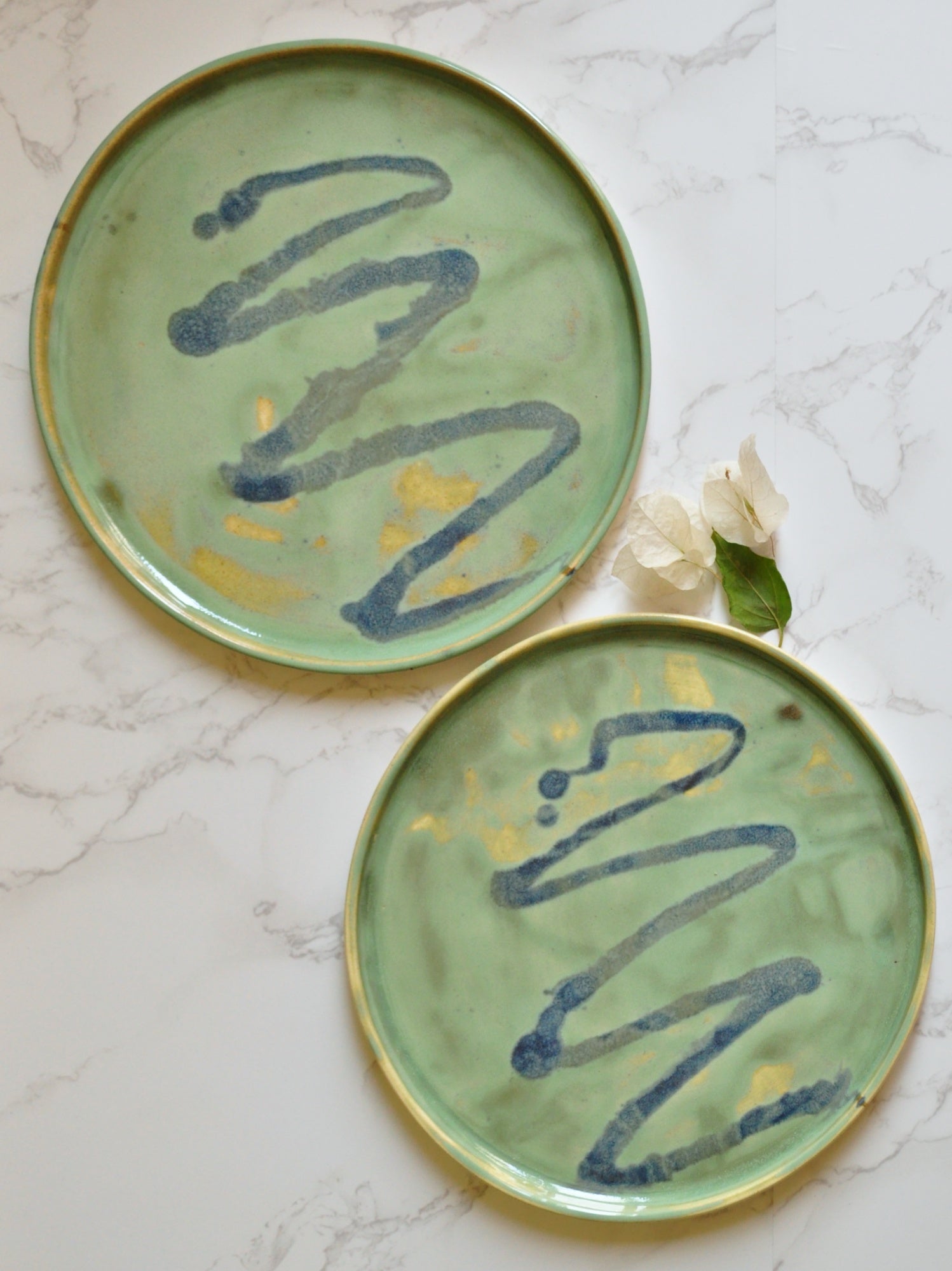 Top view of circular plates with blue splashes, made in stoneware clay and glazed in Magic Mint green glaze.