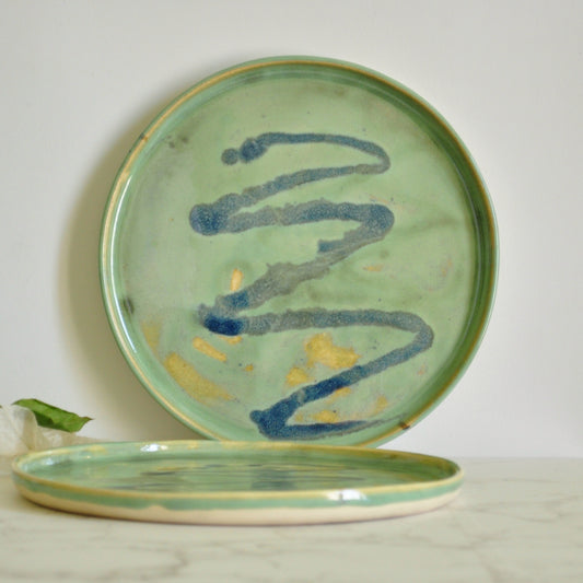 Circular plates with blue splashes, made in stoneware clay and glazed in Magic Mint green glaze.