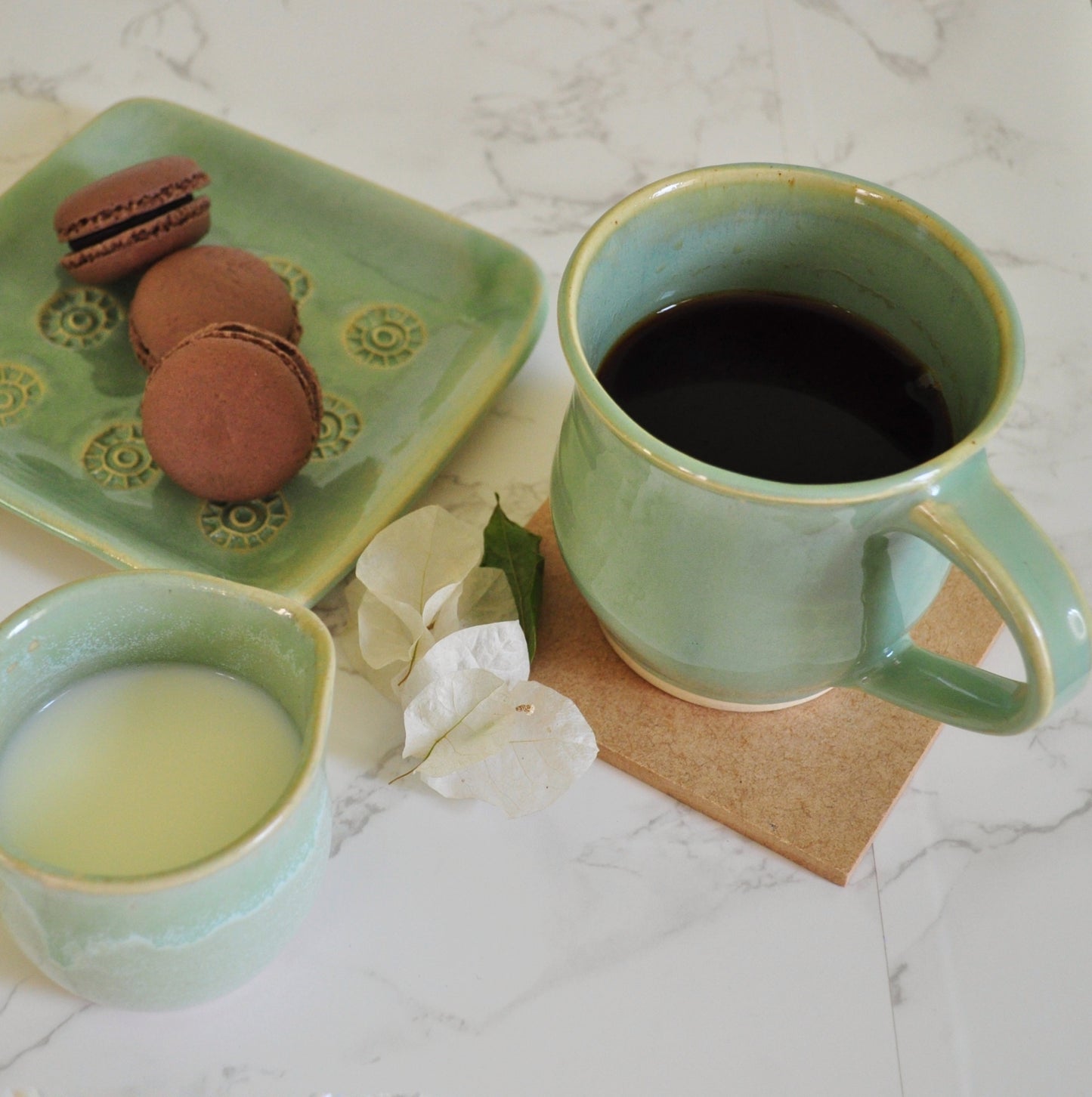 Classic tea time scene of tea mug, milk pourer, macaroons on snack plate from Magic Mint green collection. 